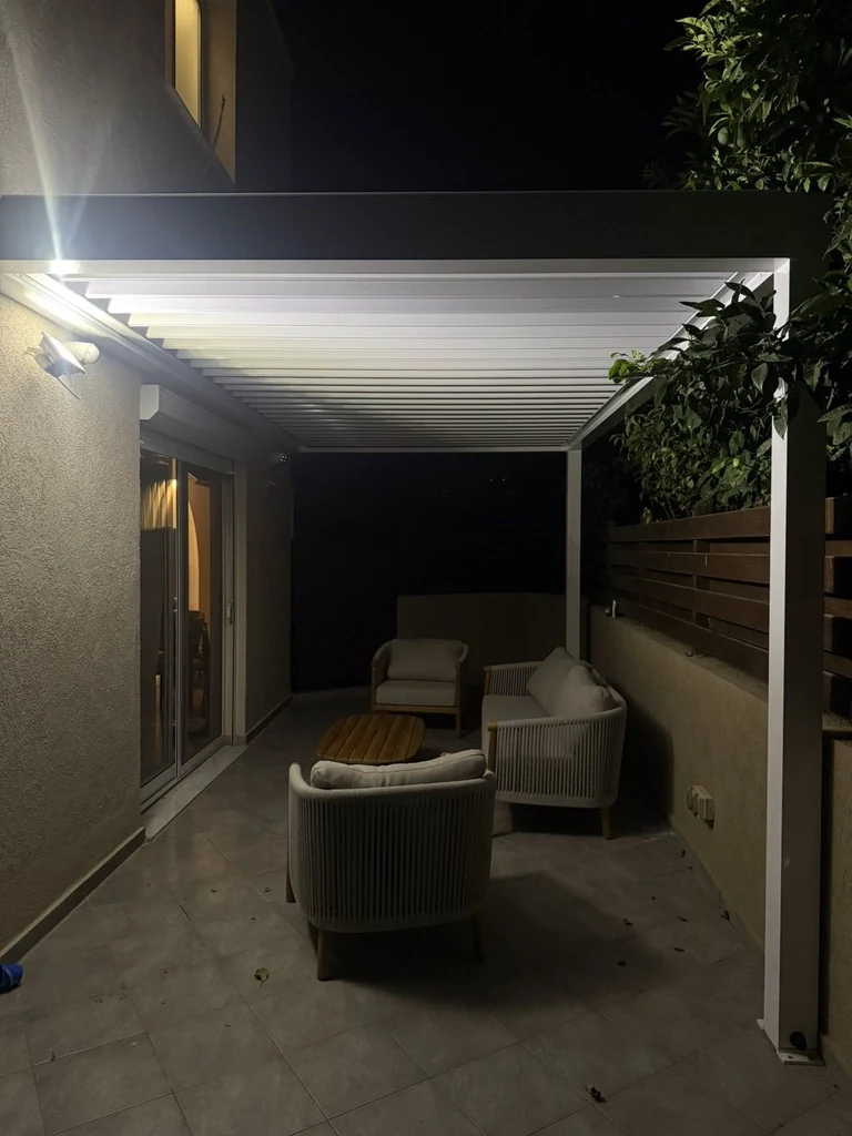 Compact white aluminium pergola with evening lighting by Protent Cyprus
